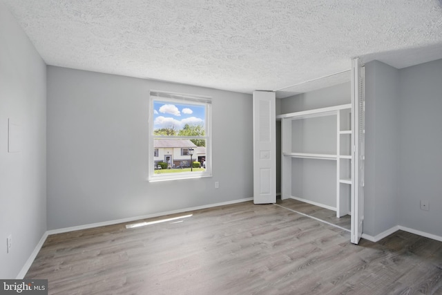 5694 Singletree Dr, Frederick, MD 21703 - unfurnished bedroom with wood finished floors, a textured ceiling, baseboards, and a closet