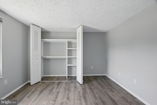 5694 Singletree Dr, Frederick, MD 21703 - unfurnished bedroom with wood finished floors, a textured ceiling, a closet, and baseboards