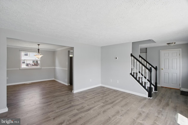 5694 Singletree Dr, Frederick, MD 21703 - unfurnished living room with a textured ceiling, wood finished floors, stairs, baseboards, and ornamental molding