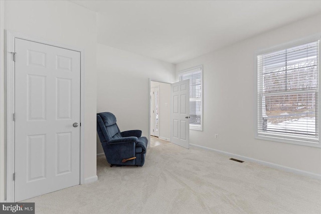 living area featuring baseboards, visible vents, and carpet