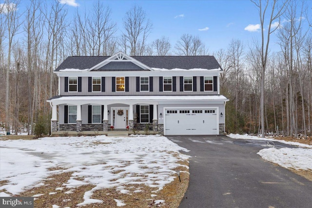 view of front of property featuring covered porch, an attached garage, stone siding, and aphalt driveway