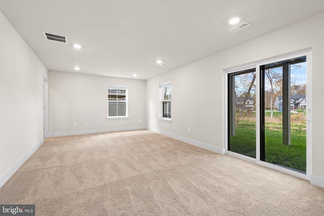 spare room featuring baseboards, visible vents, recessed lighting, and light colored carpet