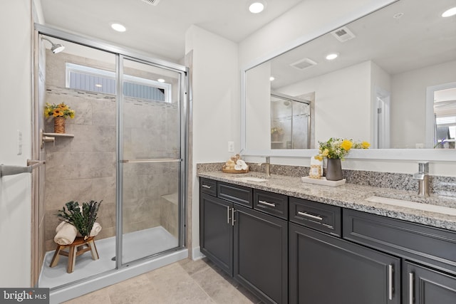 bathroom featuring double vanity, a shower stall, visible vents, and a sink