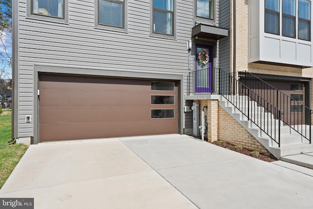 property entrance featuring a garage, brick siding, and concrete driveway