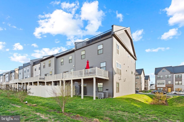 back of house featuring central AC, a residential view, and a lawn