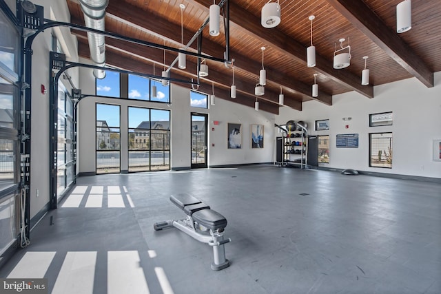 exercise room featuring baseboards, wooden ceiling, and a towering ceiling