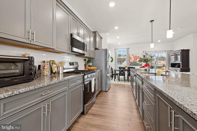 kitchen with a toaster, a sink, light wood-style floors, gray cabinets, and appliances with stainless steel finishes