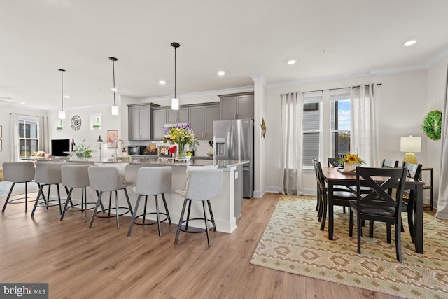 kitchen with crown molding, a spacious island, a breakfast bar, stainless steel fridge, and gray cabinets