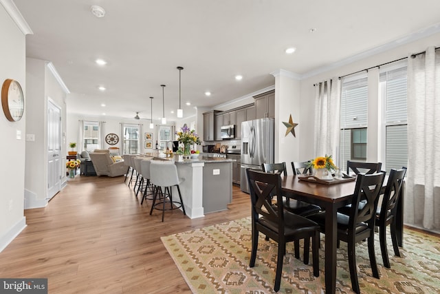 dining area featuring recessed lighting, light wood-style flooring, crown molding, and baseboards