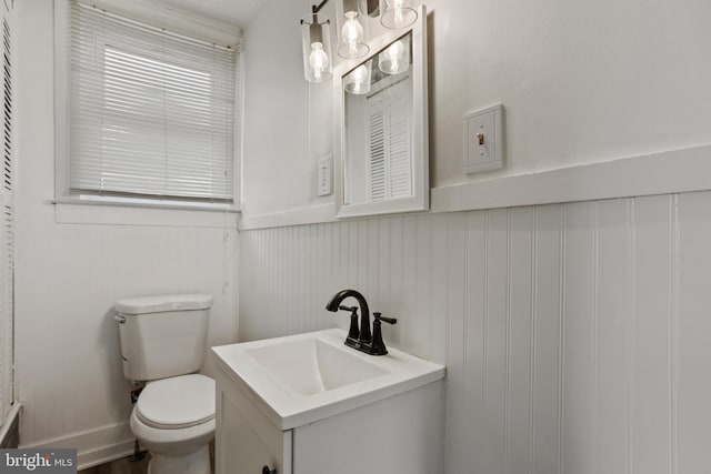 bathroom featuring wainscoting, toilet, and vanity