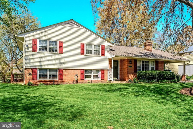 split level home with brick siding, a chimney, and a front lawn
