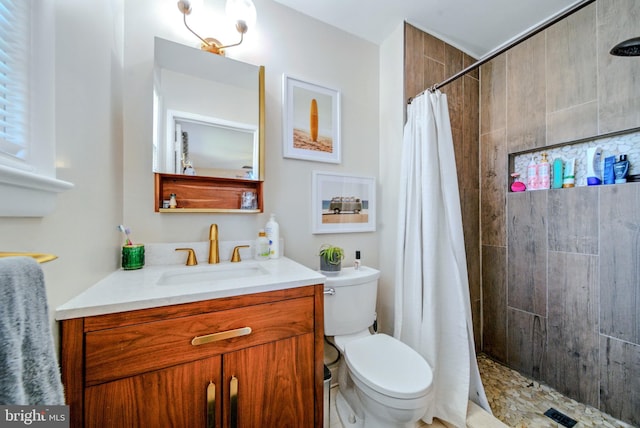 full bath with toilet, a tile shower, and vanity