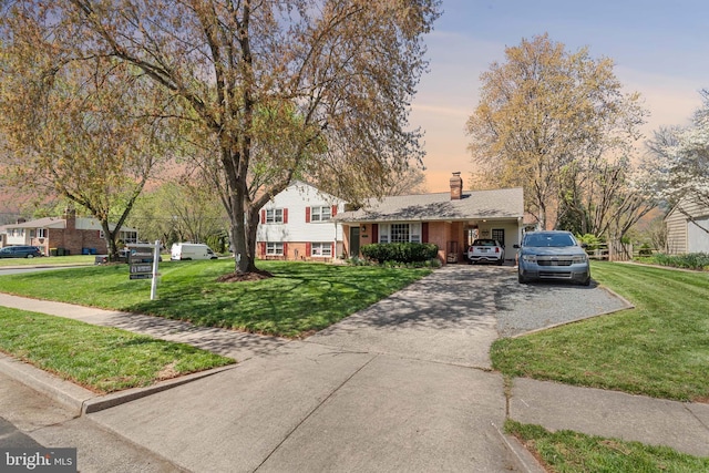 split level home with a chimney, driveway, and a front yard