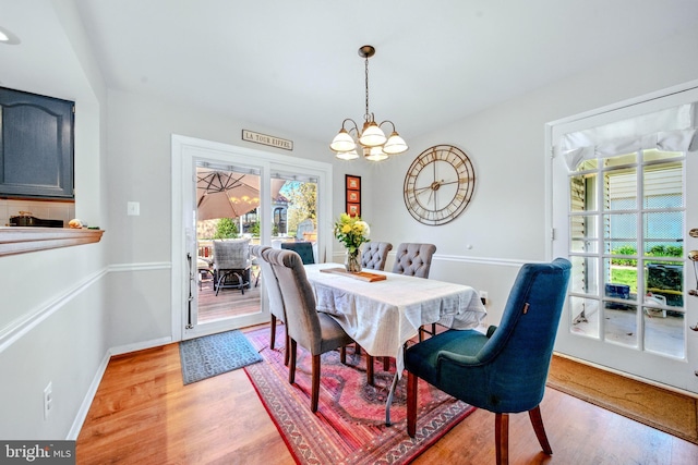 dining space with light wood-type flooring, a chandelier, and a healthy amount of sunlight