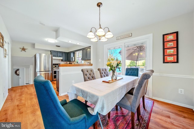 dining room featuring light wood finished floors, an inviting chandelier, and baseboards