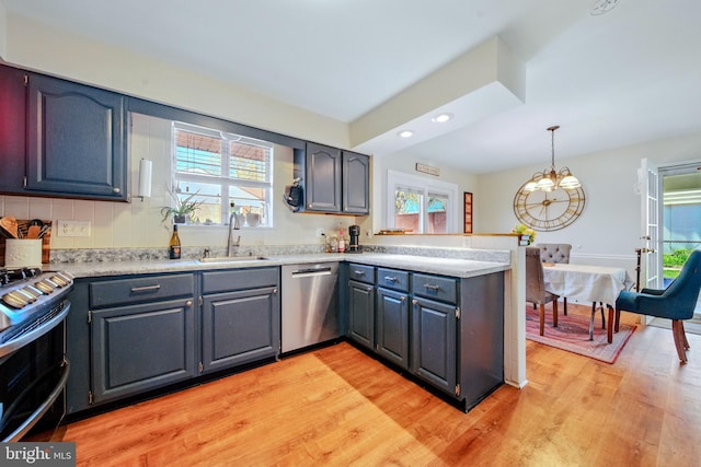 kitchen featuring a sink, light wood-type flooring, a peninsula, range with two ovens, and stainless steel dishwasher