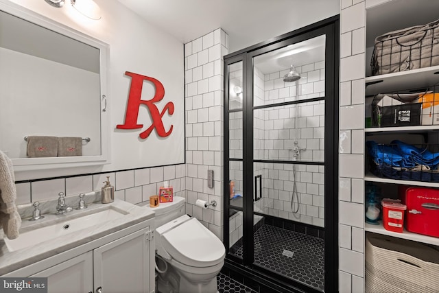bathroom featuring a stall shower, vanity, toilet, tile walls, and tile patterned flooring