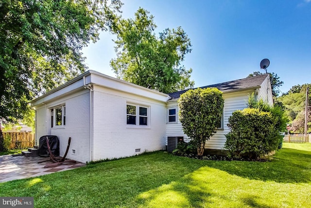 back of house with crawl space, a patio area, brick siding, a yard, and fence
