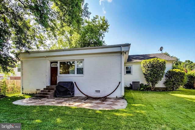 back of house with a lawn, entry steps, a patio area, fence, and brick siding