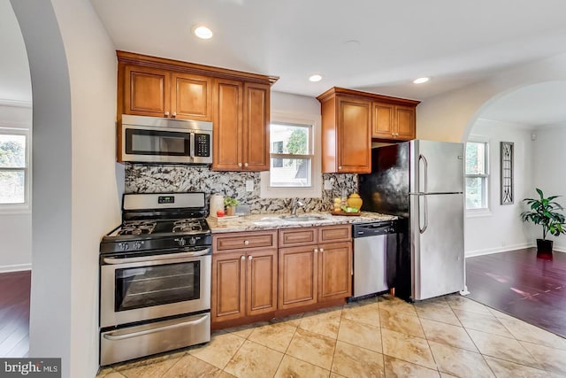 kitchen featuring a wealth of natural light, appliances with stainless steel finishes, and arched walkways