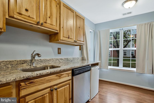 kitchen with a sink, light stone countertops, dishwasher, baseboards, and visible vents