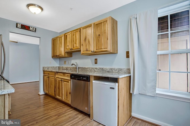 kitchen featuring dishwasher, refrigerator, light stone countertops, and light wood finished floors
