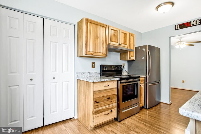 kitchen featuring a ceiling fan, appliances with stainless steel finishes, under cabinet range hood, light wood-type flooring, and light stone counters