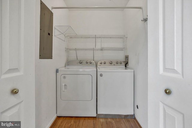 washroom featuring electric panel, baseboards, washing machine and dryer, laundry area, and wood finished floors