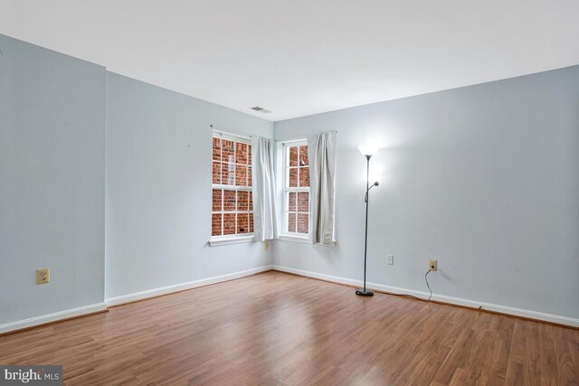 unfurnished room featuring visible vents, baseboards, and wood finished floors
