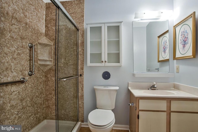bathroom featuring a stall shower, toilet, and vanity