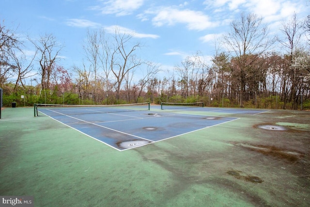 view of tennis court featuring community basketball court and fence