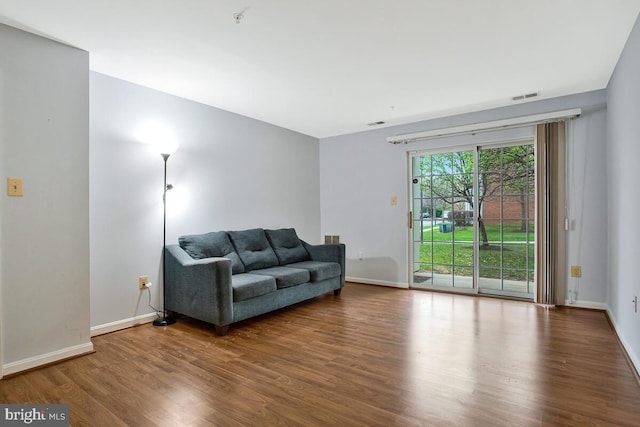 living room featuring visible vents, baseboards, and wood finished floors