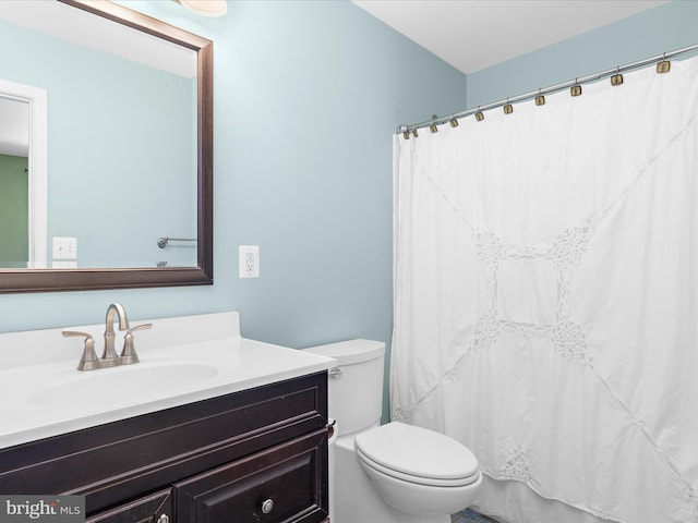full bathroom featuring a shower with shower curtain, vanity, and toilet
