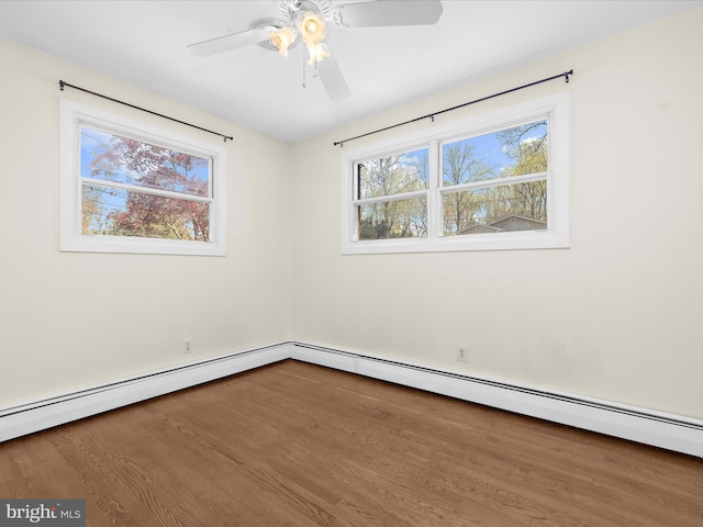 spare room featuring a wealth of natural light, ceiling fan, a baseboard radiator, and wood finished floors