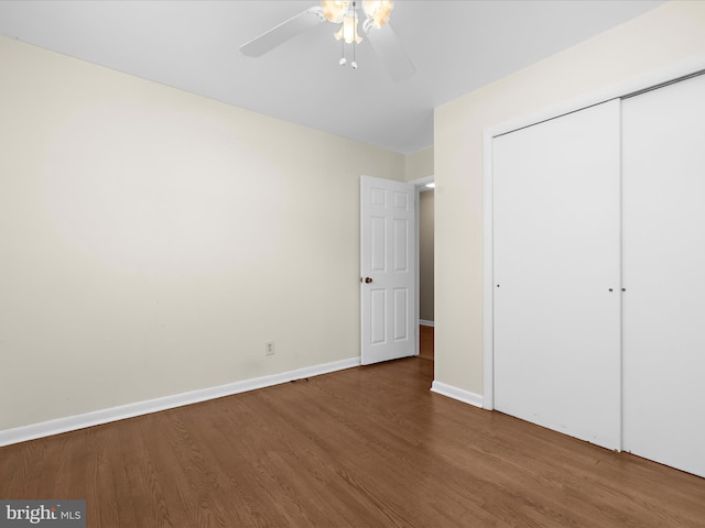 unfurnished bedroom with wood finished floors, ceiling fan, baseboards, and a closet