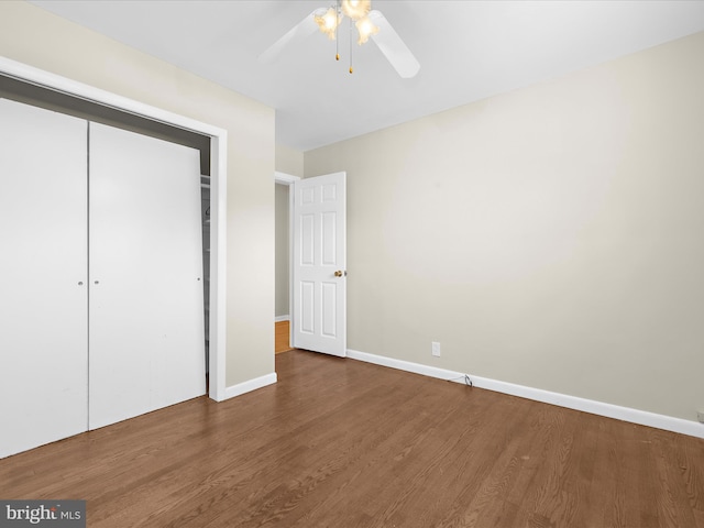 unfurnished bedroom with wood finished floors, a closet, a ceiling fan, and baseboards