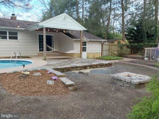 back of property with a fenced in pool, a patio, fence, and an outdoor fire pit