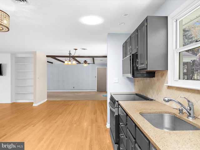 kitchen with light wood-style flooring, tasteful backsplash, a chandelier, a sink, and range with electric stovetop