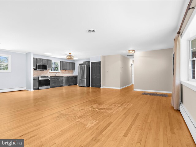 unfurnished living room with light wood-type flooring, visible vents, a baseboard radiator, and baseboards