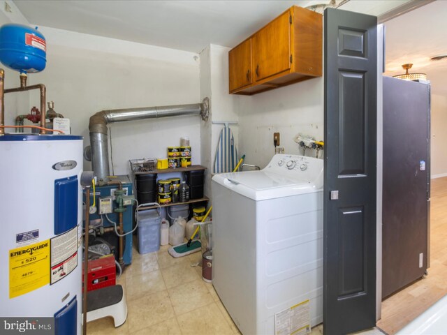 washroom with cabinet space, electric water heater, and washer / dryer
