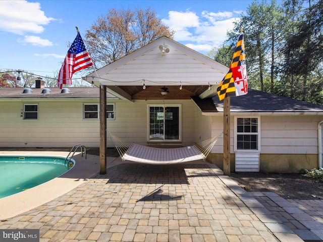back of house with an outdoor pool, a ceiling fan, a shingled roof, and a patio