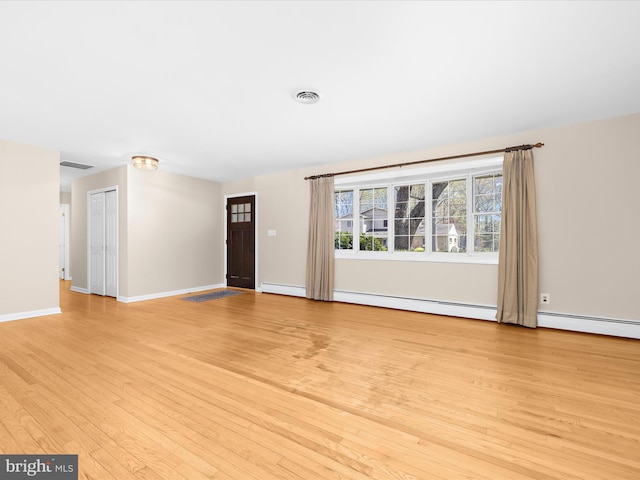 unfurnished living room featuring a baseboard radiator, light wood finished floors, baseboards, and visible vents