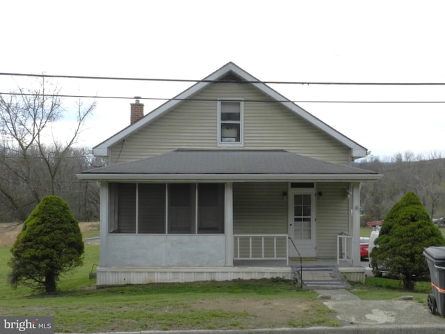 bungalow-style home featuring a porch, roof with shingles, and a chimney