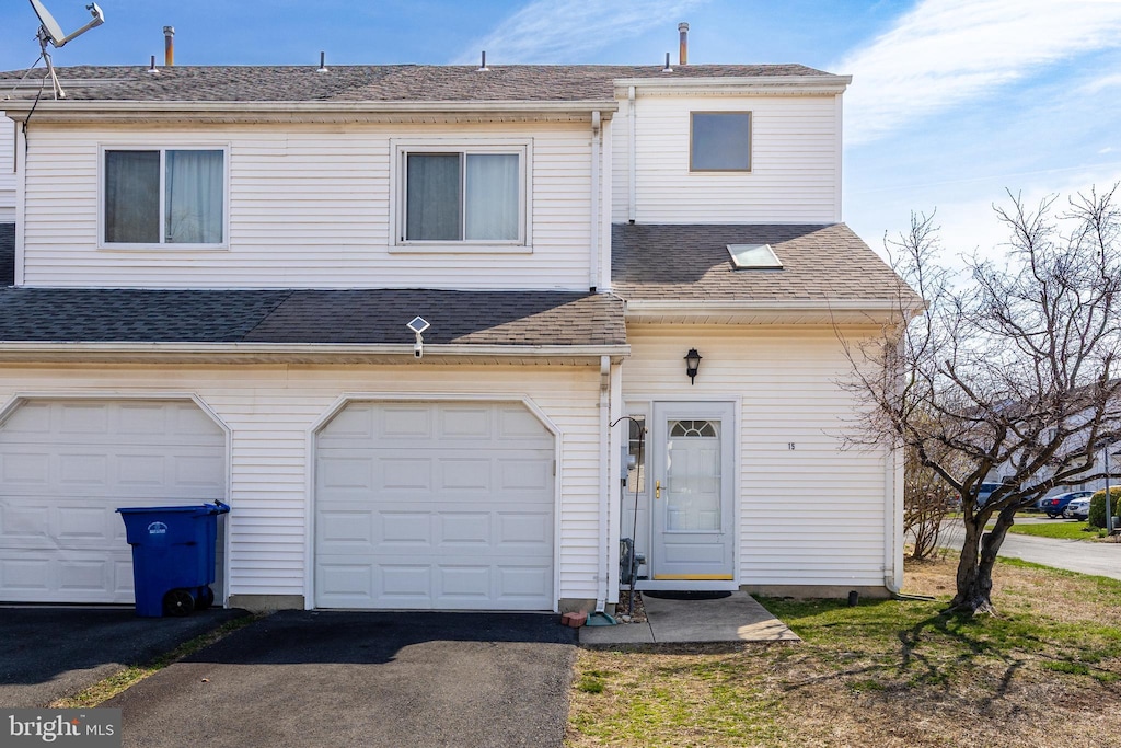 view of property featuring a shingled roof, a garage, and aphalt driveway