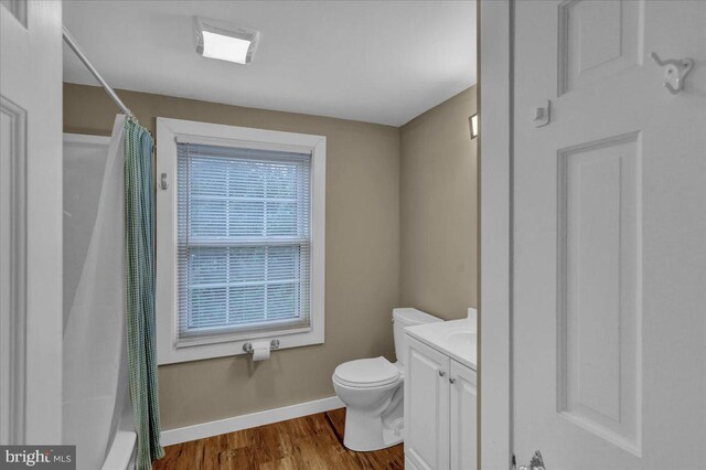 bathroom featuring toilet, vanity, wood finished floors, and baseboards