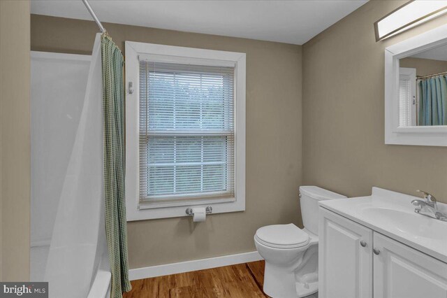 bathroom featuring vanity, toilet, curtained shower, wood finished floors, and baseboards