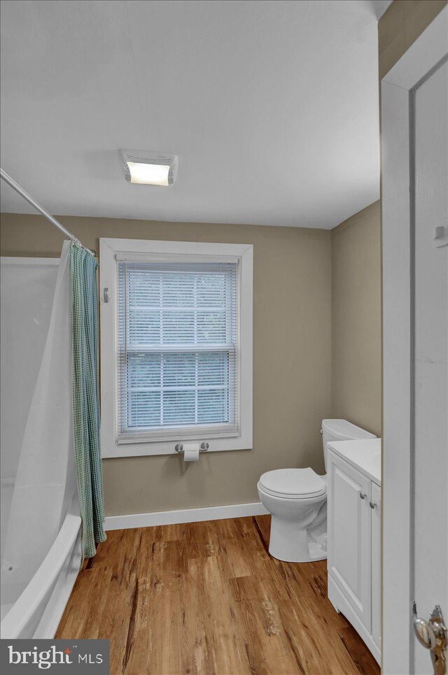 full bathroom with vanity, toilet, shower / bath combo, wood finished floors, and baseboards