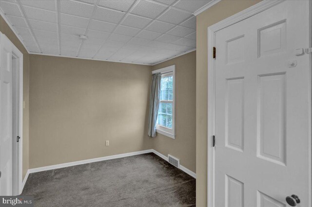 unfurnished bedroom with baseboards, a paneled ceiling, dark colored carpet, and visible vents