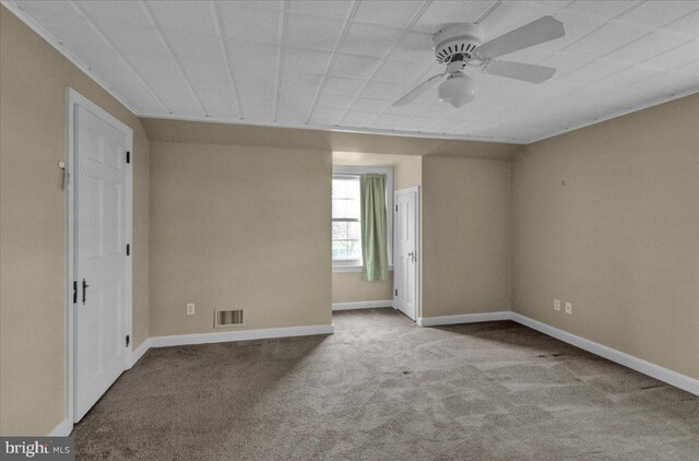 carpeted empty room with visible vents, baseboards, and a ceiling fan