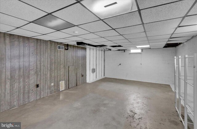 finished below grade area with wood walls and a drop ceiling